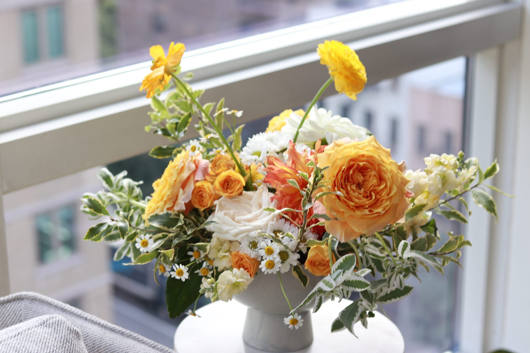 Amber-toned arrangement styled in natural light on a city balcony