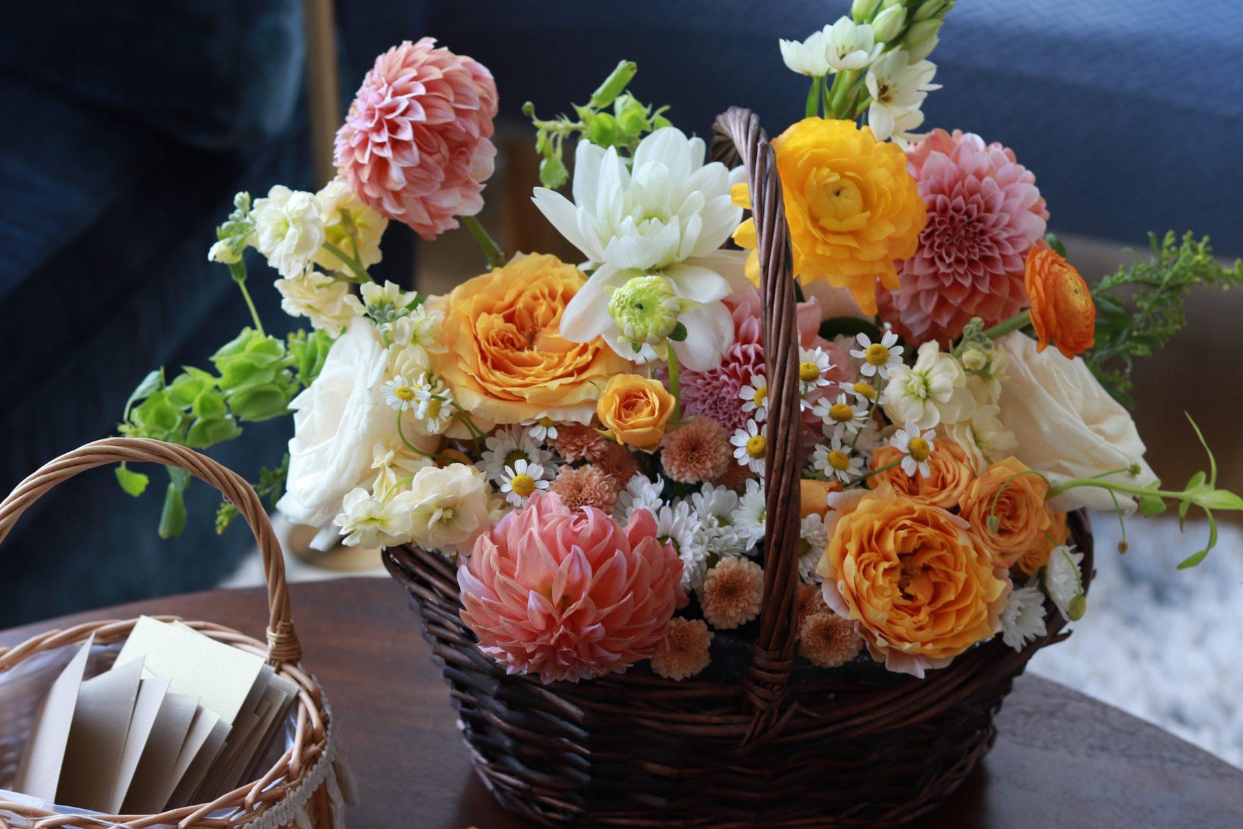 Dahlia and garden rose arrangement in a woven basket