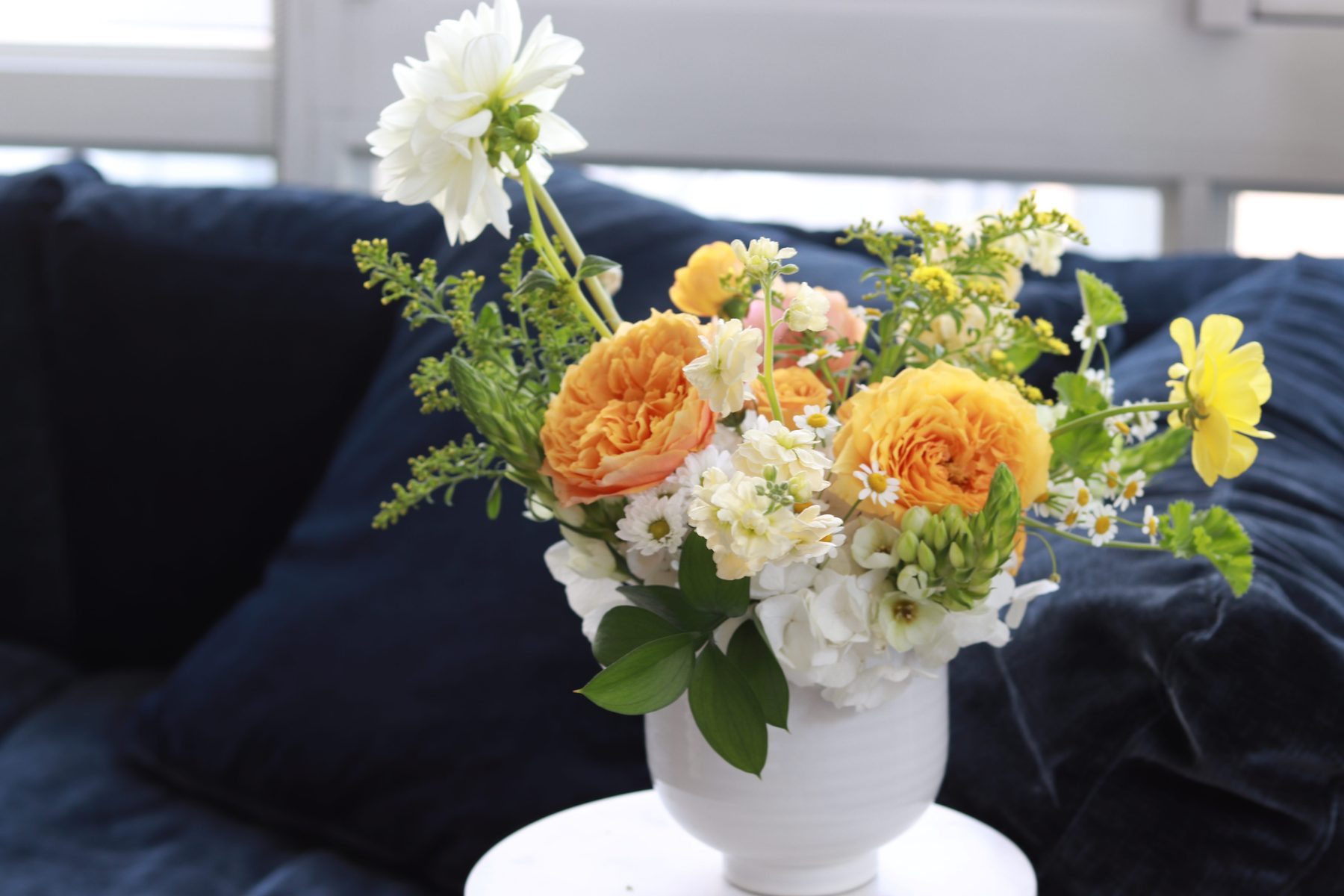 Orange garden rose and white dahlia arrangement in a white vase