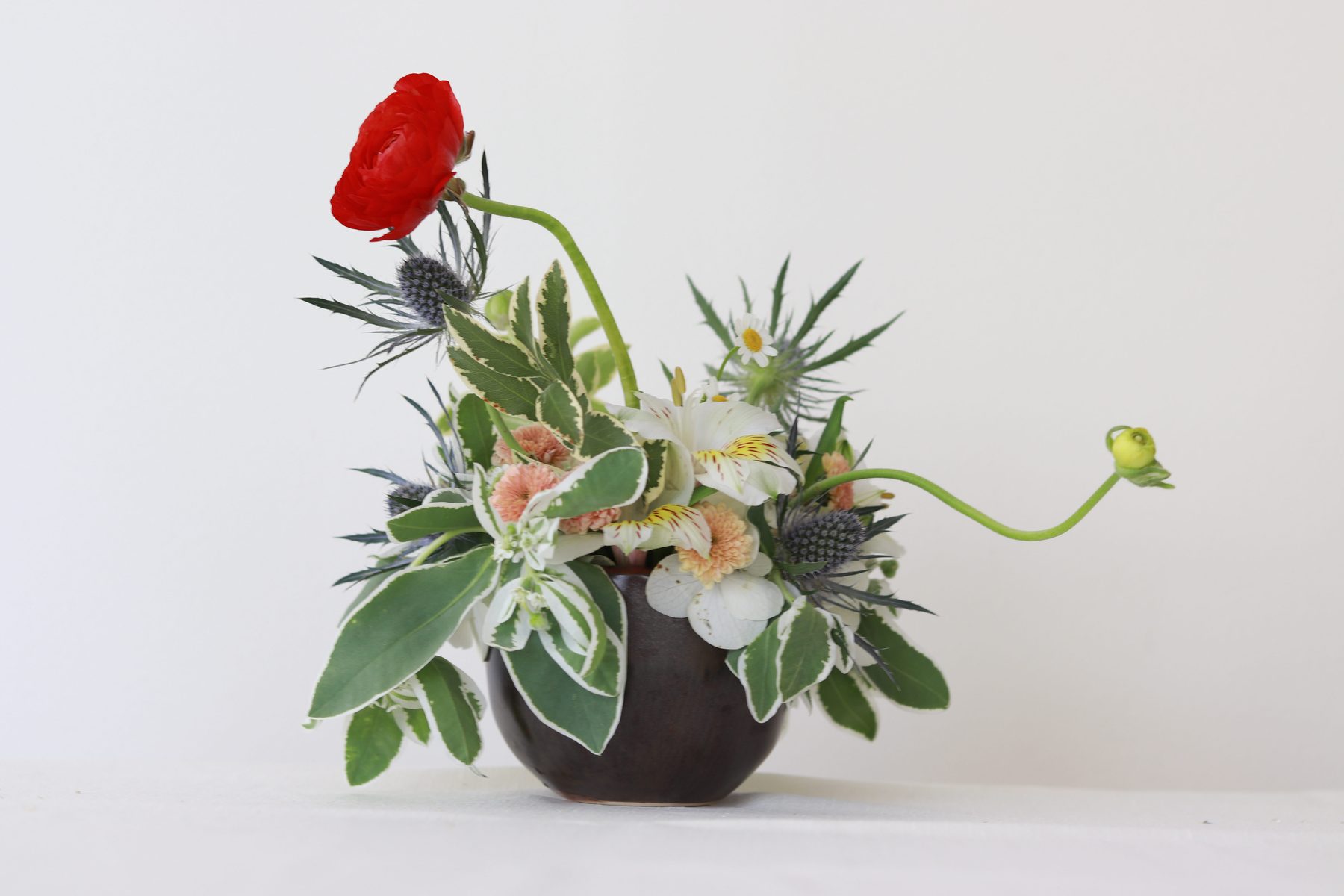 Sculptural sea holly and red ranunculus arrangement, alternate angle