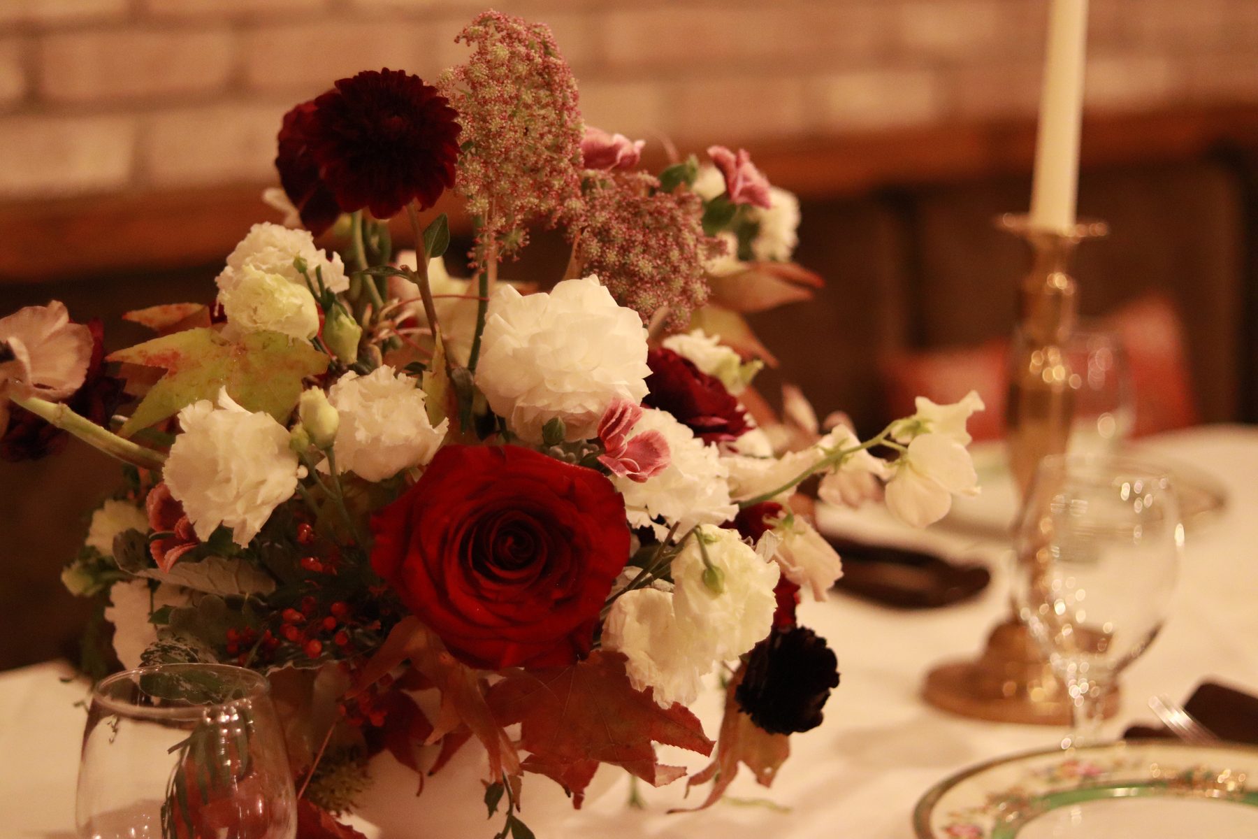 Close detail of a burgundy rose and dahlia dinner centerpiece