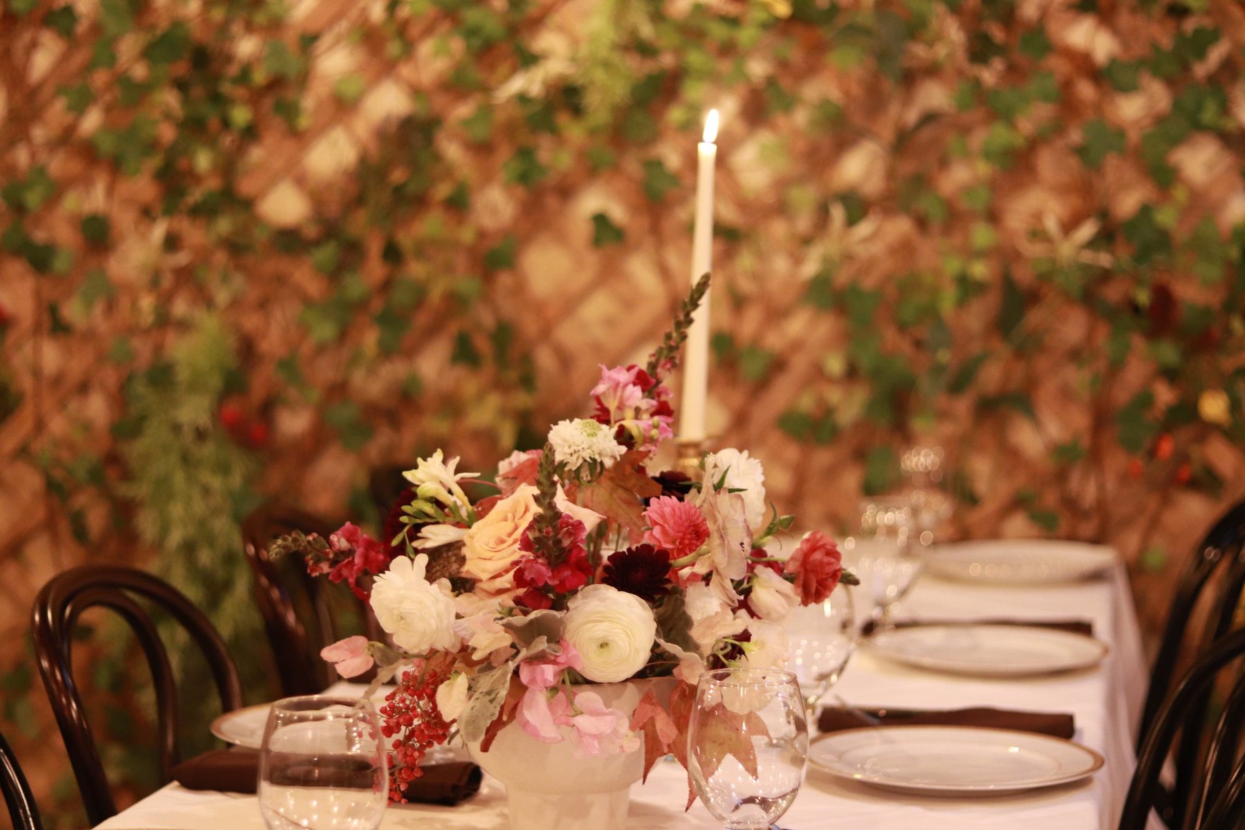 Burgundy and blush centerpiece with a taper candle on a set dinner table
