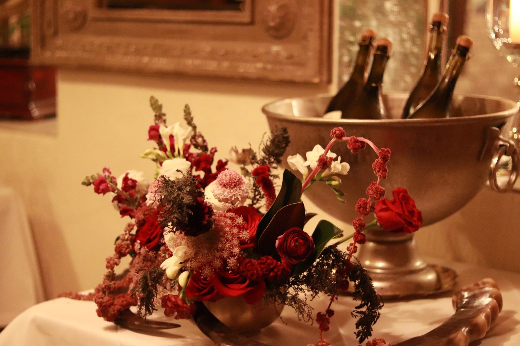 Burgundy florals styled beside a bucket of wine bottles