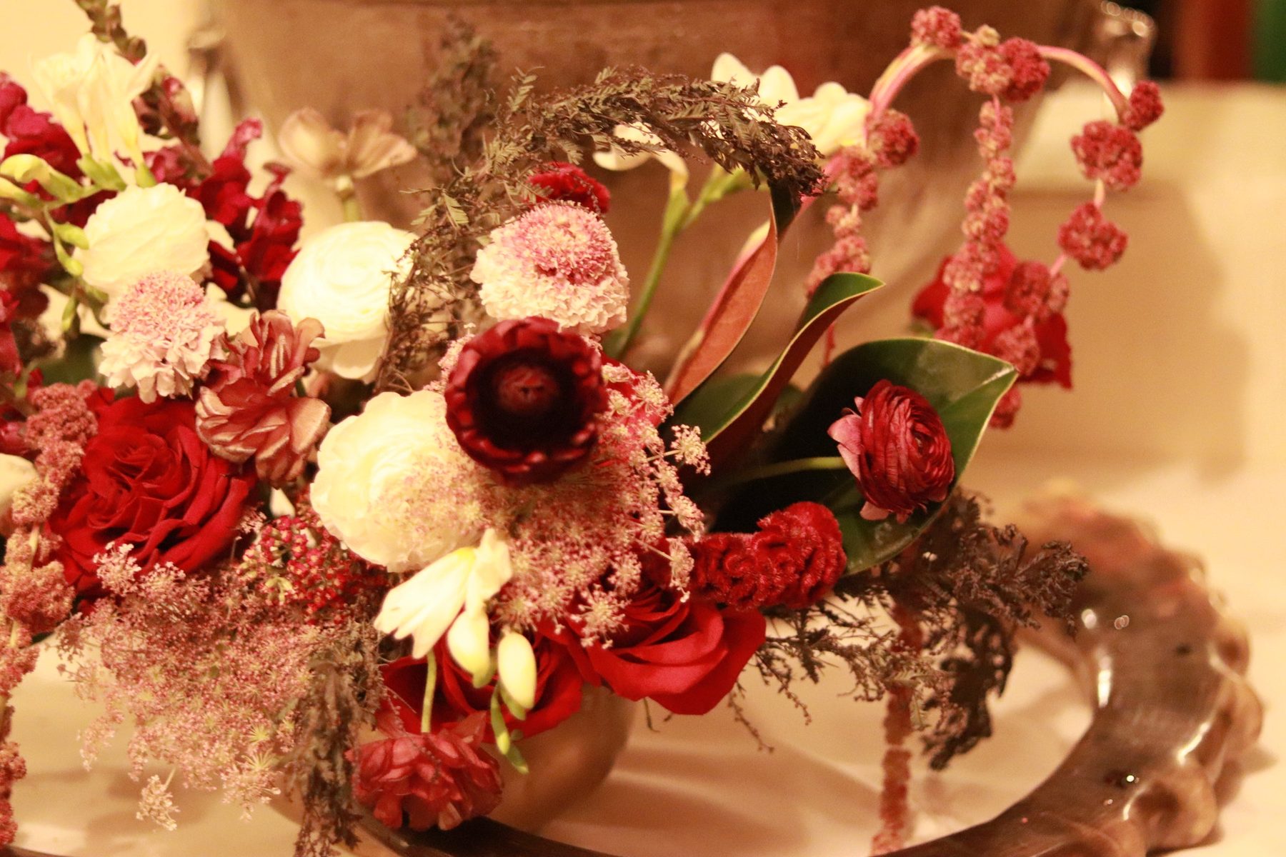 Detail of burgundy ranunculus, roses, and amaranthus on a tray
