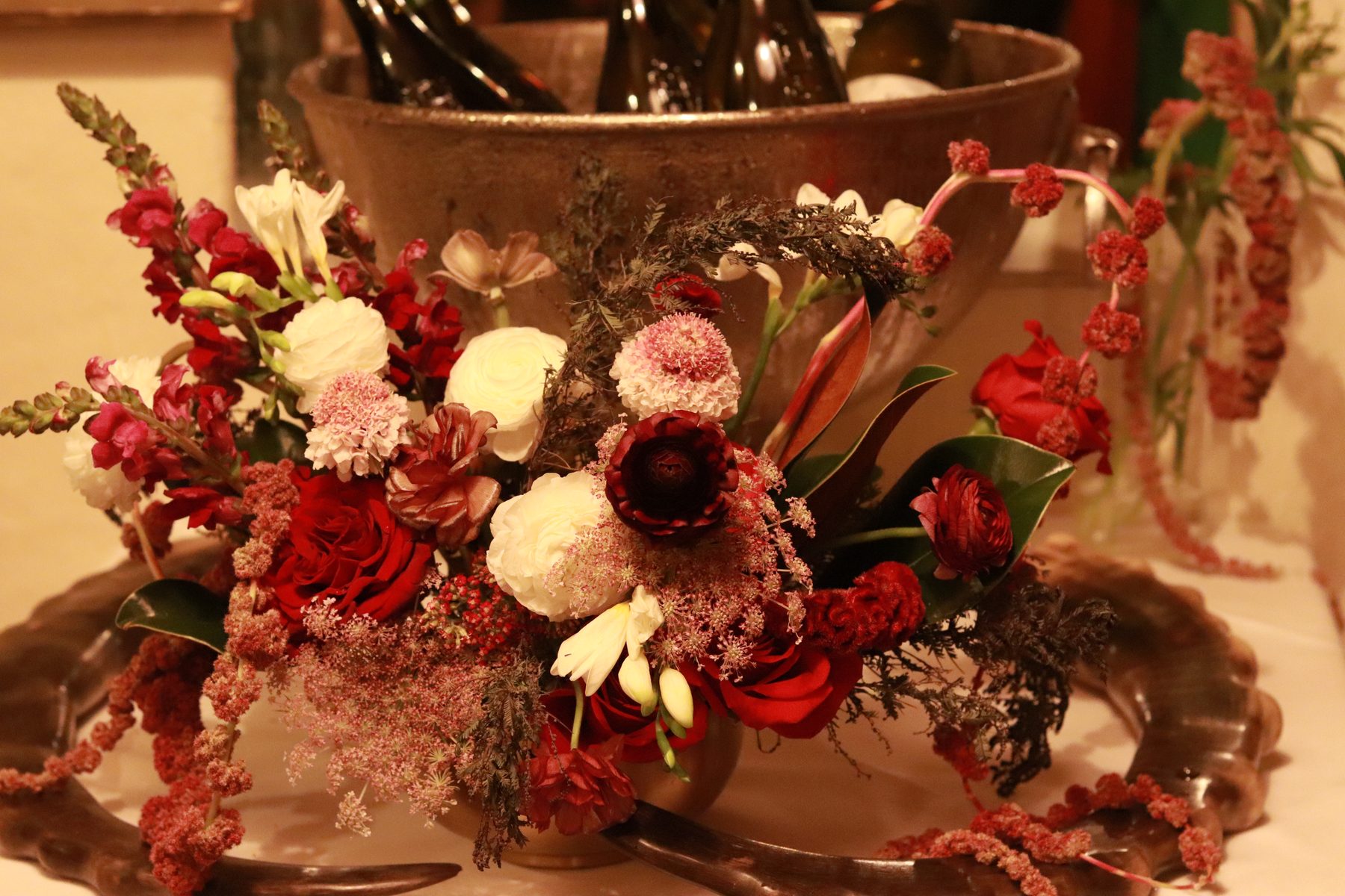 Burgundy florals styled around a bucket of wine bottles