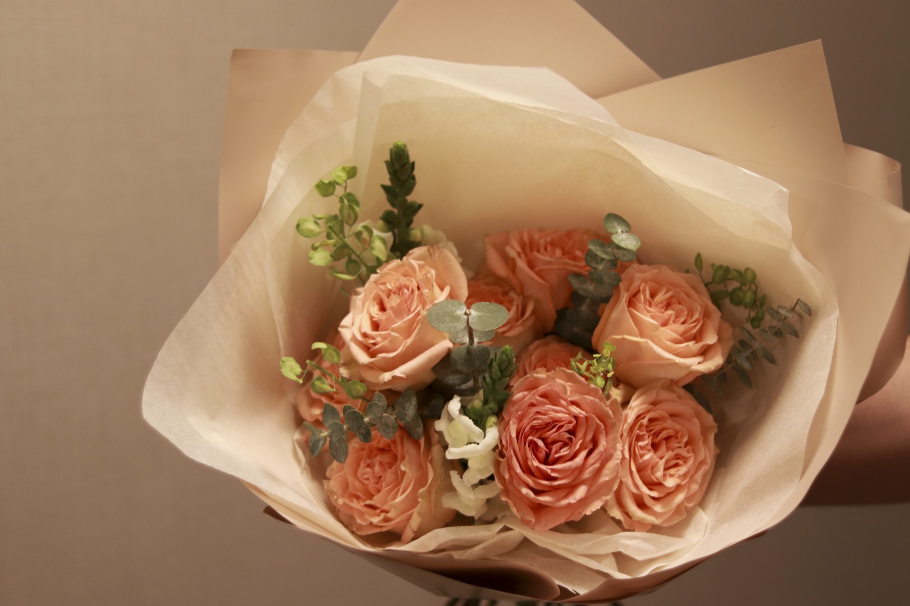 Peach garden rose bouquet wrapped in blush paper with eucalyptus