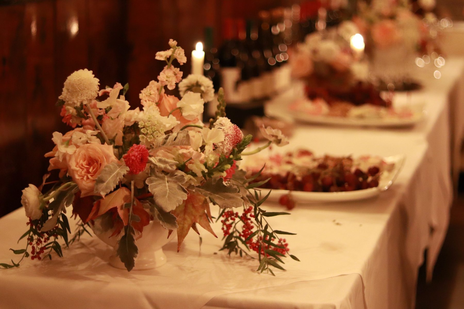 Peach, blush, and cream centerpiece with berries on a candlelit reception table